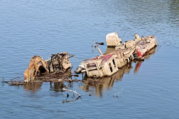 在蓝色的河里 一艘船的残骸生锈了 图库照片