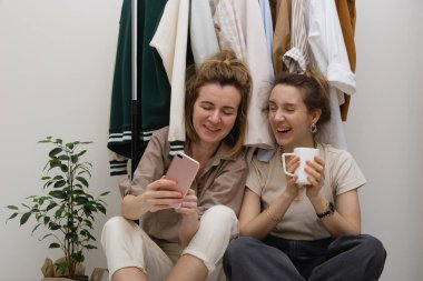 Kostüm organizasyonu konsepti. Elbise rafının yanında gülen iki kadın arkadaş..