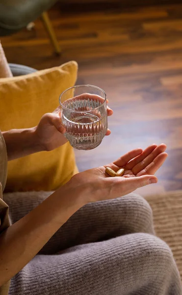 Woman takes vitamin pills at home. Close up.