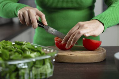 Kadın sebze salatası pişirmek için domates kesiyor. Ev mutfağı.