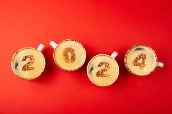 New year 2024 lettering on coffee cups on red background.