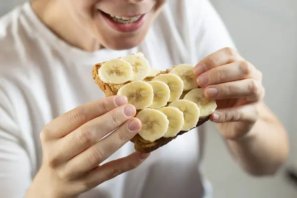 Eating sandwich with peanut butter and banana. American breakfast concept.