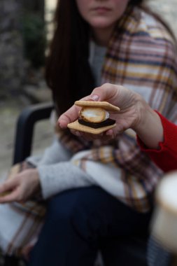 Bir kadın elinde lokum tutuyor, klasik bir kamp ateşi ziyafeti..