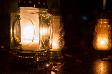 Gece bir mezarlıkta yanan adak mumu.