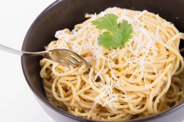 Sarı biberli spagetti rendelenmiş mozzarella peyniri ile kaplanmış kişniş soslu ve çatalla sarılmış.