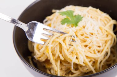 Sarı biberli spagetti rendelenmiş mozzarella peyniri ile kaplanmış kişniş soslu ve çatalla sarılmış.