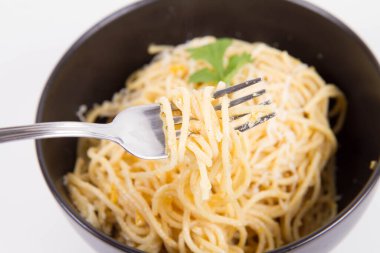 Sarı biberli spagetti rendelenmiş mozzarella peyniri ile kaplanmış kişniş soslu ve çatalla sarılmış.