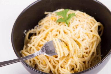 Sarı biberli spagetti rendelenmiş mozzarella peyniri ile kaplanmış kişniş soslu ve çatalla sarılmış.
