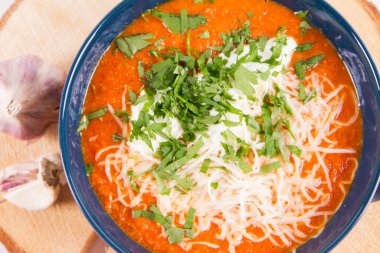 İtalyan domates çorbası, krema, mozarella peyniri ve sarımsakla süslenmiş ahşap bir tabakta taze maydanozla servis edilir.