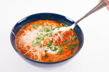 Kremayla servis edilen İtalyan domates çorbası, mozzarella peyniri ve bir kasede taze maydanoz, kaşıkla yenir.