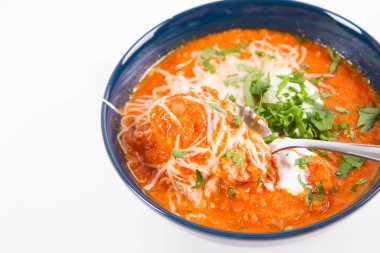 Kremayla servis edilen İtalyan domates çorbası, mozzarella peyniri ve bir kasede taze maydanoz, kaşıkla yenir.