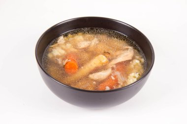 Chicken soup with noodle and carrot and parsley roots, chicken meat visible, in a bowl on a white background
