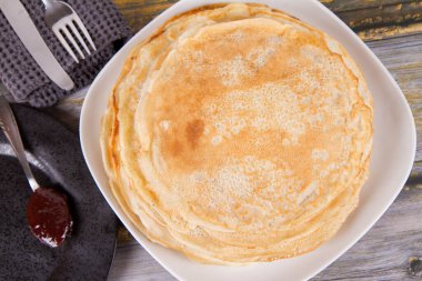 Pile of crepes with some plum jam on the side