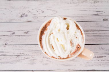 Cup of hot chocolate with whipped cream on a wooden background