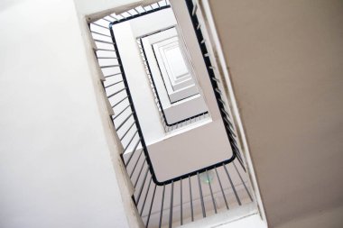 Metal parmaklıklı bir apartmanın merdivenleri yukarı doğru görünüyor.