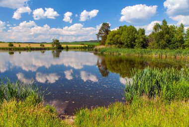 Beautiful view of pond, clouds mirroring in lake, view from bohemian and moravian highland, Czech Republic
