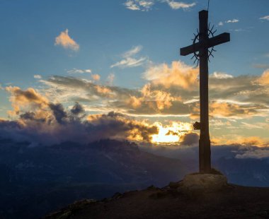 cross at the top of the hillsummit cross on the top of mount Col di Lana, evening sunset view clipart
