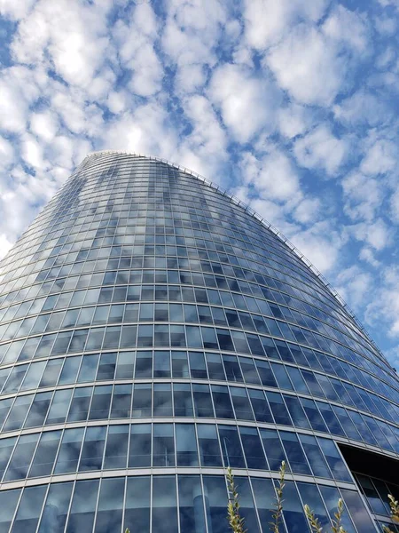stock image bottom up view of a modern office building against a blue sky with white clouds sunny weather. Blue and white style