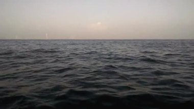 Sakin bir deniz manzarası yumuşak, puslu bir gökyüzünün altında ufka doğru yuvarlanan yumuşak dalgalarla birlikte alacakaranlıkta sakin ve huzurlu bir atmosfer yaratır. Sahne, sakin ve sessiz bir duyguyu çağrıştırıyor.