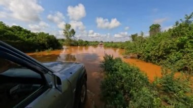 4x4 adventure drive in Madagascar. Road from Tsingy de Bemaraha to Morondava. Car partially under water. Wheel close up in muddy road. Off-road vehicle on road after rain in the countryside