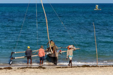 ANAKAO, MADAGASCAR - 24 Kasım 2022: Toliara 'dan Anakao' ya mal taşımak için kanoyu boşaltan adamlar. Malagasy geleneksel teknesi yüzyıllardır kullanılıyor..