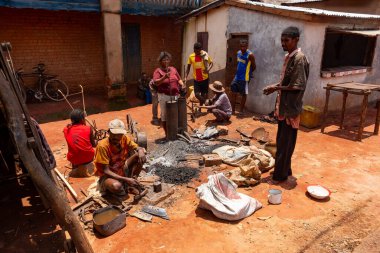 Mandoto, Madagaskar - 9 Kasım 2022 - Bir Malagasy çifti Mandoto 'da demircilik işi yapıyor. Bir Malagasy demircisi demirle çalışırken karısı atölyesindeki körükleri çalıştırıyor..