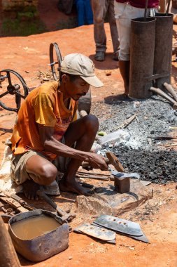 Mandoto, Madagaskar - 9 Kasım 2022 - Bir Malagasy çifti Mandoto 'da demircilik işi yapıyor. Bir Malagasy demircisi demirle çalışırken karısı atölyesindeki körükleri çalıştırıyor..