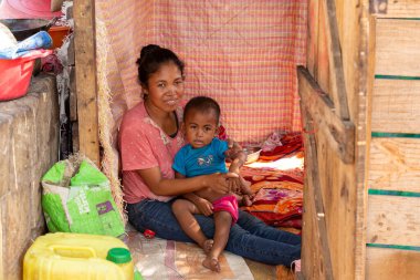 Miandrivazo, Madagaskar - 2 Kasım. 2022: Genç anne ve çocukları evlerinin önünde.