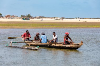MoronDAVA, MADAGASCAR - 22 Kasım 2022: Malagasy ailesi Morondava, Madagaskar 'da geleneksel ahşap botla nehri geçiyor.