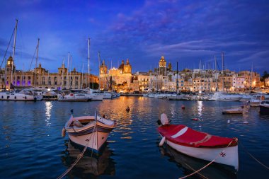 Senglea şehri, Malta 'nın üç şehrinin bir parçası. Gece marinası gece gökyüzünün altında parlıyor. Yat direkleri, sakin suları yansıtan parıldayan ışıklara karşı. Seyahat hedefi.