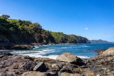Playa Ocotal ve Pasifik Okyanusu dalgaları kayalık kıyılarda, El Coco Kosta Rika. Ünlü şnorkel plajı. Resimli cennet tropikal manzarası. Pura Vida konsepti, egzotik tropikal ülkeye seyahat.