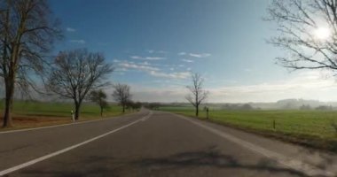 Sonbaharda araba gezintisi, arabadan POV manzarası, güneşli bir günde mavi gökyüzü olan kırsal alanda düşen renkli ağaçlar..