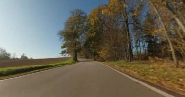 Sonbaharda araba gezintisi, arabadan POV manzarası, güneşli bir günde mavi gökyüzü olan kırsal alanda düşen renkli ağaçlar..