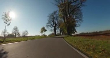 Sonbaharda araba gezintisi, arabadan POV manzarası, güneşli bir günde mavi gökyüzü olan kırsal alanda düşen renkli ağaçlar..