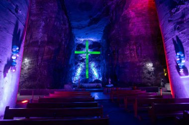 Illuminated cross representing stations of the cross, illustrate the events of Jesus last journey glows with spiritual light in the underground Catedral de Sal (Salt Cathedral) of Zipaquira, Colombia. clipart