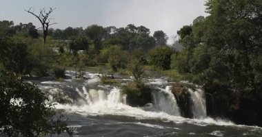 Zimbabwe 'deki görkemli Victoria Şelalesi, gürleyen şelale yemyeşil orman zeminine karşı devasa yağmur bulutları ve gökkuşakları yaratıyor. Zambezi Nehri 'ndeki doğal dünya harikası. Afrika vahşi doğası.