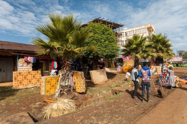 Demebecha, Ethiopia - April 20 2019: Street vendors display patterned mattresses for sale under palm trees on a dirt lot in the town of Demebecha.