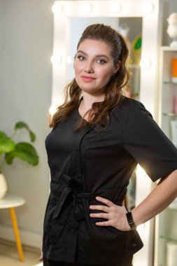 Parlak masaj spa stüdyosunda siyah cüppeli beyaz bir masör. Arka planda lambalar olan bulanık bir ayna.