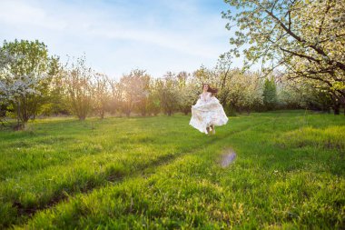 Güzel esmer beyaz bir kadının portresi. Çiçekli bir elma bahçesinde beyaz çiçekli bir elbiseyle koşuyor. Yüzünden taze yeşil çimenler fırlamış, saçları uçuşuyor.