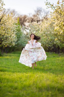 Güzel esmer beyaz bir kadının portresi. Çiçekli bir elma bahçesinde beyaz çiçekli bir elbiseyle koşuyor. Yüzünden taze yeşil çimenler fırlamış, saçları uçuşuyor.