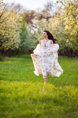 Güzel esmer beyaz bir kadının portresi. Çiçekli bir elma bahçesinde beyaz çiçekli bir elbiseyle koşuyor. Yüzünden taze yeşil çimenler fırlamış, saçları uçuşuyor.
