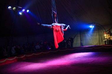 Red Arena 'da profesyonel hava çemberi kadın jimnastikçi sirk performansı. Arka planı koyu renkli ışıklarla aydınlatılmış, jimnastik unsurları sergiliyor.