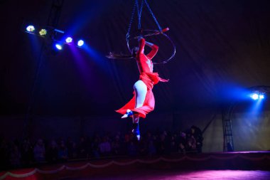 Red Arena 'da profesyonel hava çemberi kadın jimnastikçi sirk performansı. Arka planı koyu renkli ışıklarla aydınlatılmış, jimnastik unsurları sergiliyor.