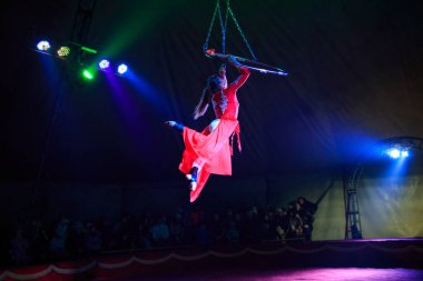Red Arena 'da profesyonel hava çemberi kadın jimnastikçi sirk performansı. Arka planı koyu renkli ışıklarla aydınlatılmış, jimnastik unsurları sergiliyor.