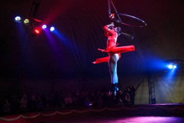 Red Arena 'da profesyonel hava çemberi kadın jimnastikçi sirk performansı. Arka planı koyu renkli ışıklarla aydınlatılmış, jimnastik unsurları sergiliyor.