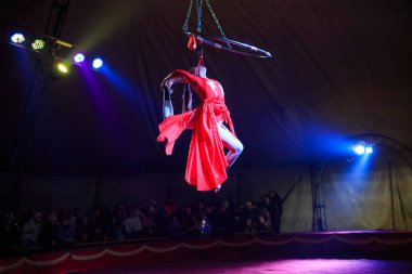 Red Arena 'da profesyonel hava çemberi kadın jimnastikçi sirk performansı. Arka planı koyu renkli ışıklarla aydınlatılmış, jimnastik unsurları sergiliyor.