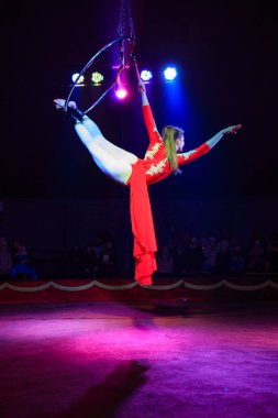 Red Arena 'da profesyonel hava çemberi kadın jimnastikçi sirk performansı. Arka planı koyu renkli ışıklarla aydınlatılmış, jimnastik unsurları sergiliyor.