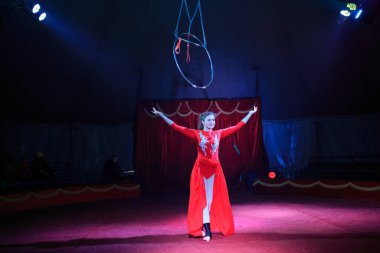 Red Arena 'da profesyonel hava çemberi kadın jimnastikçi sirk performansı. Arka planı koyu renkli ışıklarla aydınlatılmış, jimnastik unsurları sergiliyor.