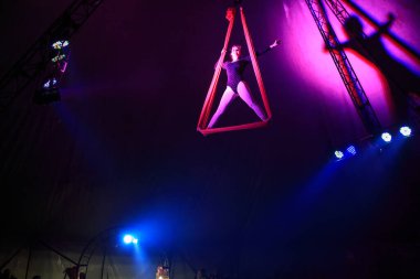 Profesyonel hava kayışları ipek kadın jimnastikçi sirk performansı Red Arena 'da arka planı koyu renkli konser ışıklarıyla aydınlatılmış, jimnastik unsuru sergiliyor.