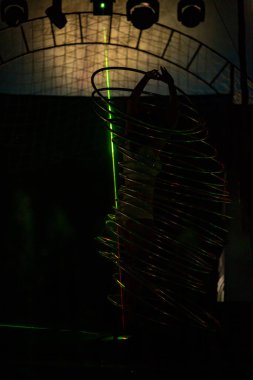 Genç, zayıf, çekici sirk jimnastikçisi kadın, kırmızı arenada hula hoopla canlı performans sergiliyor. Seyirciler heyecanlanıyor.